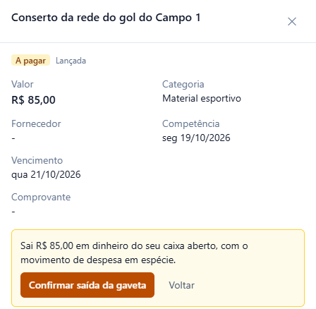 Detalhe da despesa Conserto da rede do gol do Campo 1, R$ 85,00, a pagar, categoria Material esportivo, com o quadro amarelo Sai R$ 85,00 em dinheiro do seu caixa aberto, com o movimento de despesa em espécie e os botões Confirmar saída da gaveta e Voltar.